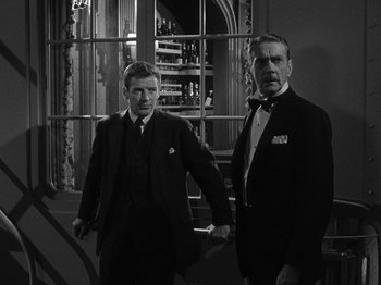 Movie still from “Titanic” (1953), directed by Jean Negulesco – Two men standing next to each other in front of a window; Medium shot, Low angle