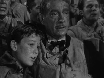 Movie still from “Titanic” (1953), directed by Jean Negulesco – An older man and a young boy are in a crowd; Medium shot, High angle