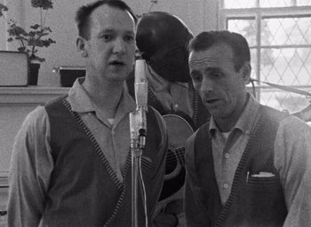 A black - and - white photo of two men in front of a microphone