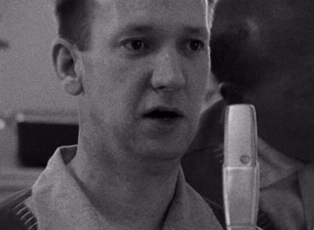 A black and white photo of a man holding a microphone