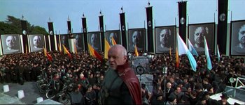 Movie still from “Titus” (1999), directed by Julie Taymor – A man in a crowd of people in front of a wall; Wide shot, High angle