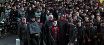 Movie still from “Titus” (1999), directed by Julie Taymor – A large group of men in black and red outfits; Wide shot, High angle