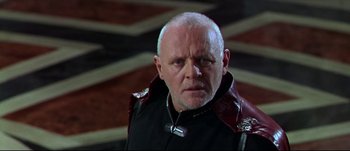 Movie still from “Titus” (1999), directed by Julie Taymor – An older man wearing a black and red jacket; Close Up shot, Low angle