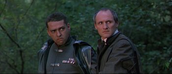 Movie still from “Titus” (1999), directed by Julie Taymor – A couple of men standing next to each other in a forest; Close Up shot, Low angle