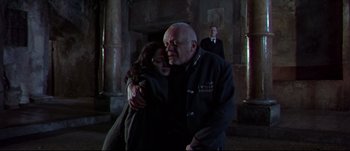 Movie still from “Titus” (1999), directed by Julie Taymor – A man and a woman hugging in a dark room; Medium shot, Low angle