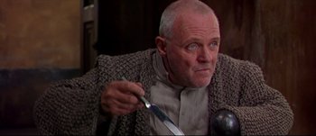 Movie still from “Titus” (1999), directed by Julie Taymor – An older man holding a knife in his right hand; Close Up shot, Over the shoulder angle