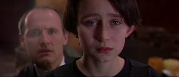 Movie still from “Titus” (1999), directed by Julie Taymor – A young girl looking sad while standing next to an older man; Close Up shot, Over the shoulder angle