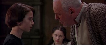 Movie still from “Titus” (1999), directed by Julie Taymor – A man and a woman face each other in front of another man; Close Up shot, Over the shoulder angle