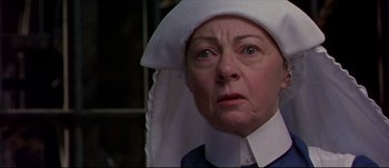 Movie still from “Titus” (1999), directed by Julie Taymor – An older woman wearing a nun's hat and looking at the camera; Close Up shot, Low angle