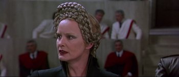 Movie still from “Titus” (1999), directed by Julie Taymor – A woman wearing a wig and a black jacket; Close Up shot, Over the shoulder angle