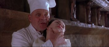 Movie still from “Titus” (1999), directed by Julie Taymor – An older man and a younger woman in a chef's outfit; Close Up shot, Low angle