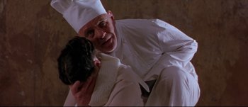 Movie still from “Titus” (1999), directed by Julie Taymor – A man in a chef's hat holding a cat; Close Up shot, Low angle