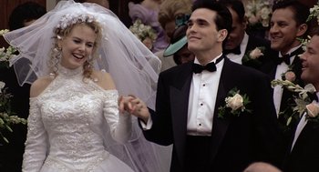 Movie still from “To Die For” (1995), directed by Gus Van Sant – A man and a woman holding hands and smiling; Medium shot, Low angle