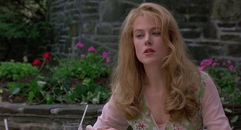 Movie still from “To Die For” (1995), directed by Gus Van Sant – A beautiful woman with long blonde hair sitting in front of flowers; Close Up shot, Over the shoulder angle