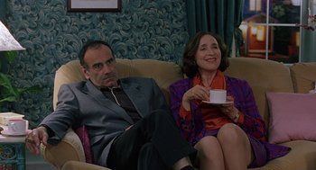 Movie still from “To Die For” (1995), directed by Gus Van Sant – A man and a woman sitting on a couch drinking coffee; Medium shot, High angle