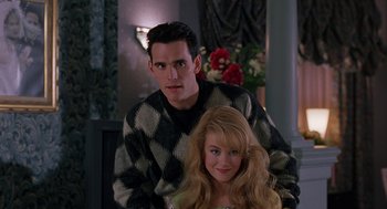 Movie still from “To Die For” (1995), directed by Gus Van Sant – A man and a woman pose for a picture; Medium shot, Over the shoulder angle