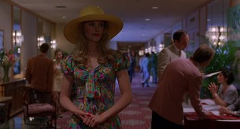 Movie still from “To Die For” (1995), directed by Gus Van Sant – A woman wearing a yellow hat standing in a hallway; Medium shot, Over the shoulder angle