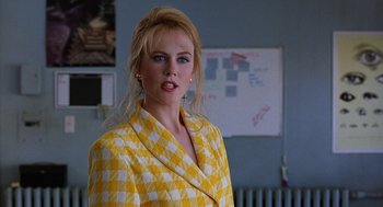 Movie still from “To Die For” (1995), directed by Gus Van Sant – A woman in a yellow checkered jacket standing in front of a whiteboard; Close Up shot, Over the shoulder angle