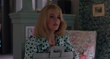 Movie still from “To Die For” (1995), directed by Gus Van Sant – A woman in a polka dot shirt is holding a bag; Medium shot, Over the shoulder angle