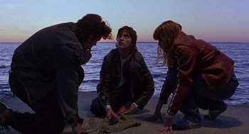 Movie still from “To Die For” (1995), directed by Gus Van Sant – A group of people standing on top of a sandy beach; Medium shot, High angle