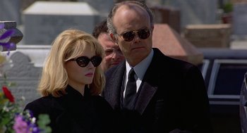 Movie still from “To Die For” (1995), directed by Gus Van Sant – A man and a woman wearing sunglasses and black suits; Medium shot, Low angle