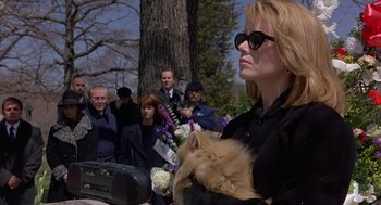 Movie still from “To Die For” (1995), directed by Gus Van Sant – A woman holding a cat in her arms while standing in front of a crowd of onlookers; Medium shot, Low angle