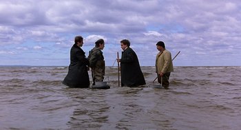 Movie still from “To Die For” (1995), directed by Gus Van Sant – A group of people in the water holding sticks; Wide shot, High angle