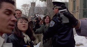 Movie still from “To Die For” (1995), directed by Gus Van Sant – A police officer talking to a crowd of people; Medium shot, Over the shoulder angle