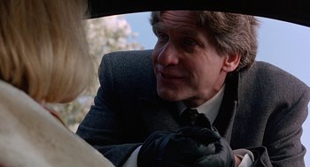 Movie still from “To Die For” (1995), directed by Gus Van Sant – A person wearing a suit and tie; Close Up shot, Over the shoulder angle