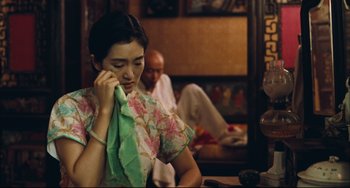 Movie still from “To Live” (1994), directed by Yimou Zhang – A woman sitting in front of a man holding a towel; Medium shot, Over the shoulder angle