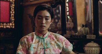Movie still from “To Live” (1994), directed by Yimou Zhang – A young woman in a floral dress is looking down; Close Up shot, Over the shoulder angle