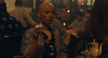 Movie still from “To Live” (1994), directed by Yimou Zhang – A man holding a cell phone in his hand; Medium shot, Over the shoulder angle