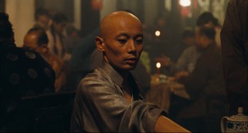 Movie still from “To Live” (1994), directed by Yimou Zhang – A man with a shaved head and a black tie; Close Up shot, Over the shoulder angle