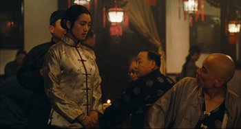Movie still from “To Live” (1994), directed by Yimou Zhang – A man and a woman are standing in a room together; Medium shot, Over the shoulder angle