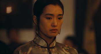 Movie still from “To Live” (1994), directed by Yimou Zhang – A young woman in a chinese dress looking to her left; Close Up shot, Over the shoulder angle