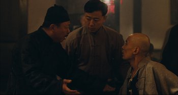 Movie still from “To Live” (1994), directed by Yimou Zhang – A group of men standing next to each other in a room; Medium shot, Over the shoulder angle