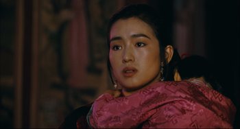 Movie still from “To Live” (1994), directed by Yimou Zhang – A woman in a pink dress is looking at the camera; Close Up shot, Over the shoulder angle