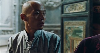 Movie still from “To Live” (1994), directed by Yimou Zhang – A man with a shaved head and a bald head looking to his left; Close Up shot, Over the shoulder angle