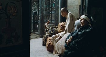 Movie still from “To Live” (1994), directed by Yimou Zhang – A group of people sitting on top of a floor; Wide shot, Over the shoulder angle