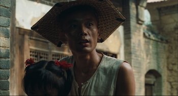 Movie still from “To Live” (1994), directed by Yimou Zhang – A man wearing a straw hat with a bird on his shoulder; Close Up shot, Low angle
