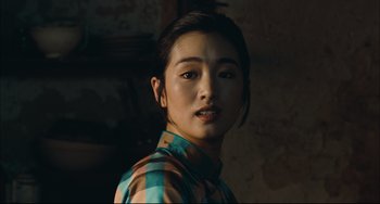 Movie still from “To Live” (1994), directed by Yimou Zhang – A young woman in a plaid shirt poses for a picture; Close Up shot, Over the shoulder angle