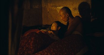 Movie still from “To Live” (1994), directed by Yimou Zhang – A man and a woman laying in a bed together; Medium shot, High angle