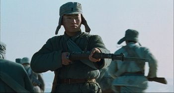Movie still from “To Live” (1994), directed by Yimou Zhang – A man in a military uniform holding a rifle; Medium shot, Low angle
