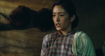 Movie still from “To Live” (1994), directed by Yimou Zhang – A woman in a plaid shirt is looking at the camera; Medium shot, Over the shoulder angle