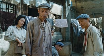 Movie still from “To Live” (1994), directed by Yimou Zhang – A group of men standing next to each other in front of a building; Medium shot, Low angle