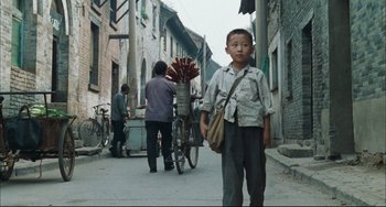 Movie still from “To Live” (1994), directed by Yimou Zhang – A young boy standing on the side of the street; Wide shot, Low angle