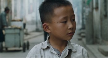 Movie still from “To Live” (1994), directed by Yimou Zhang – A young asian boy with a black dot on his forehead; Close Up shot, High angle