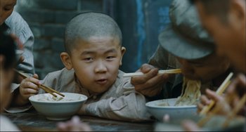 Movie still from “To Live” (1994), directed by Yimou Zhang – A young boy is eating noodles with a spoon; Close Up shot, Over the shoulder angle