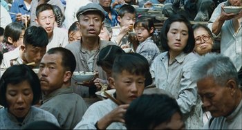Movie still from “To Live” (1994), directed by Yimou Zhang – A group of people sitting around eating food; Medium shot, High angle
