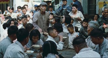 Movie still from “To Live” (1994), directed by Yimou Zhang – A large group of people sitting at a table eating food; Wide shot, High angle